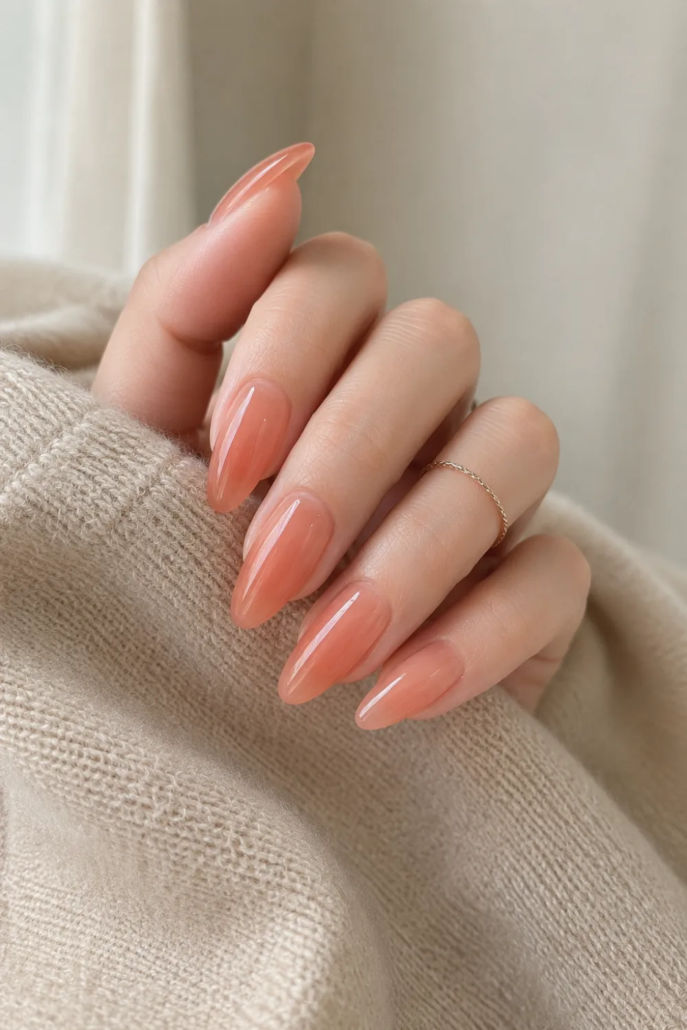 Peach nude jelly almond nails featuring a soft translucent gel finish, glossy shine, natural peach tones, and a minimalist manicure perfect for a polished everyday style.