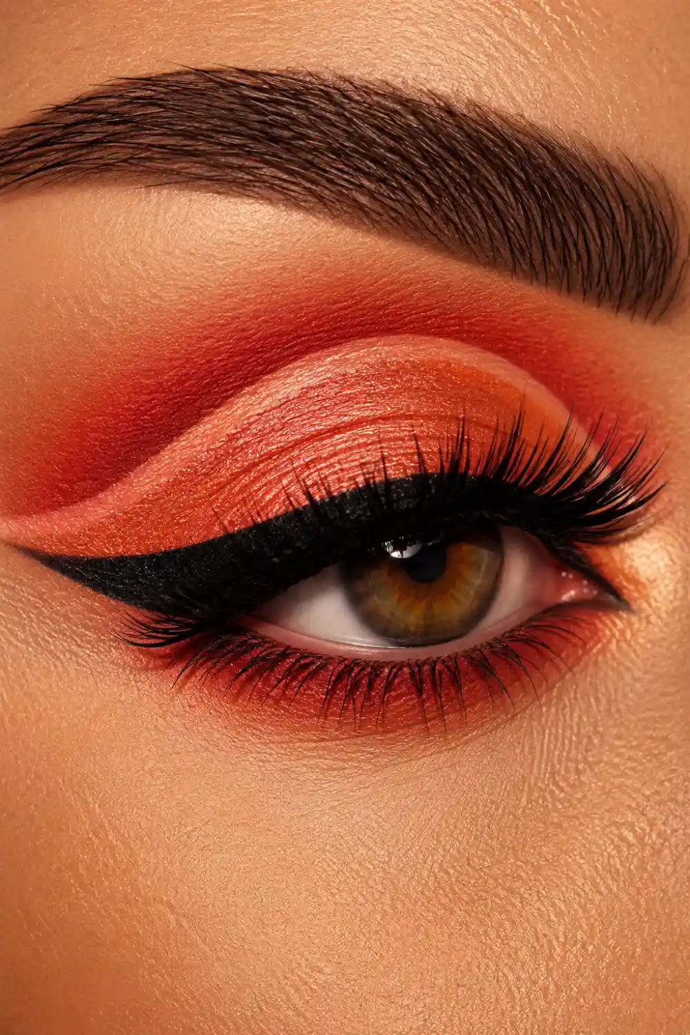 Bold coral cut crease eye makeup with vibrant coral shades, dramatic black winged eyeliner, voluminous lashes, sharp definition, and colorful summer beauty inspiration for statement makeup lovers.
