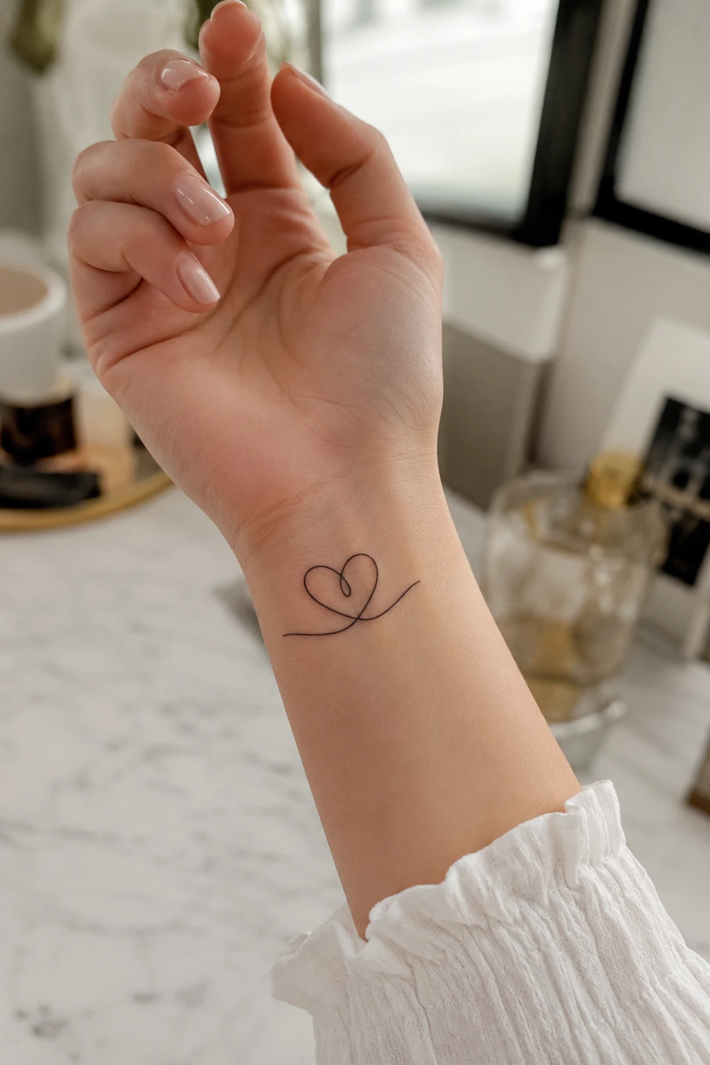 Heart line drawing tattoo on a woman's wrist featuring minimalist continuous line artwork, elegant black ink heart design, feminine tattoo inspiration, modern fine line tattoo style, and delicate body art.