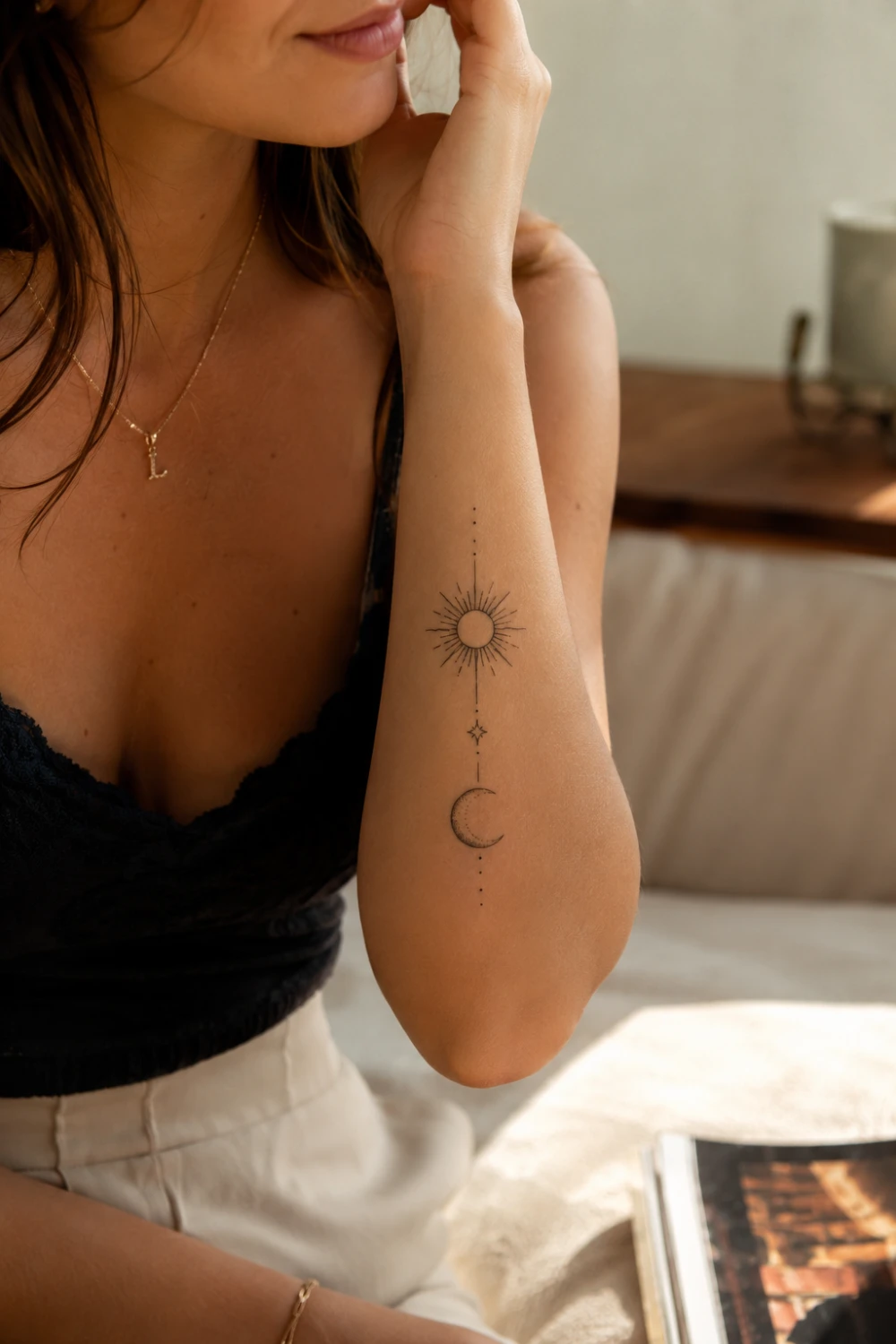 Sun and moon tattoo on a woman's forearm featuring celestial fine line artwork, minimalist black ink tattoo design, feminine spiritual tattoo inspiration, elegant body art, and modern aesthetic tattoo trends.